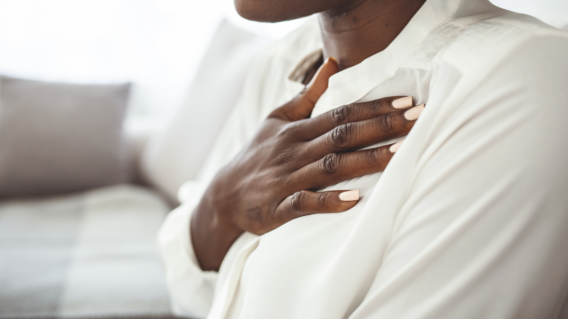 Girl having respiration problems touching chest sitting on a couch in the living room at home.