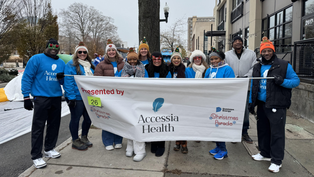Accessia Health staff stands outside holding up a banner that reads 